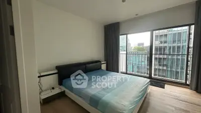 Modern bedroom with large windows and city view in high-rise apartment