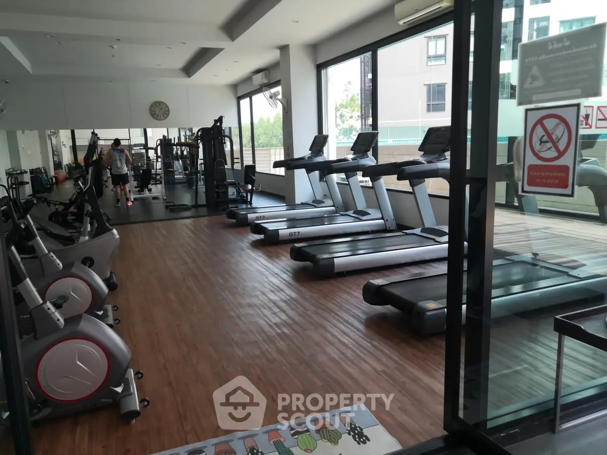 Spacious gym with modern equipment and large windows for natural light.