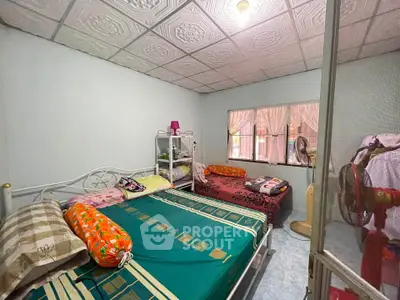 Cozy bedroom with two beds, decorative ceiling, and natural light from window.