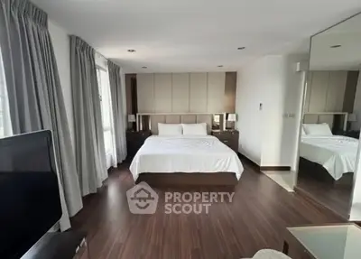 Spacious modern bedroom with elegant decor and large windows for natural light.