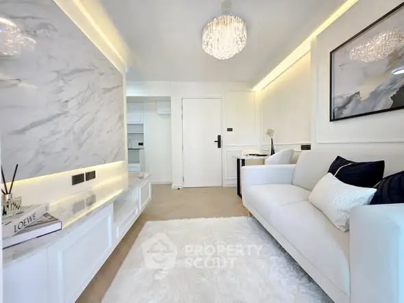 Luxurious modern living room with elegant chandelier and plush white sofa.