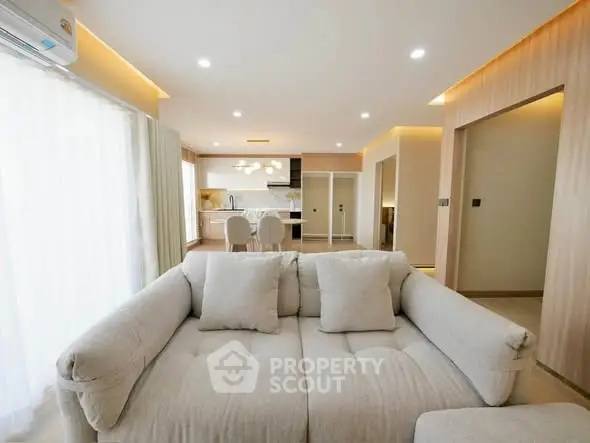 Spacious modern living room with open kitchen layout and elegant lighting