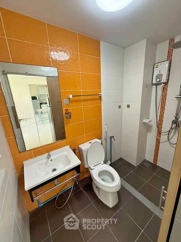 Modern bathroom with vibrant orange tiles and sleek fixtures in a contemporary apartment.