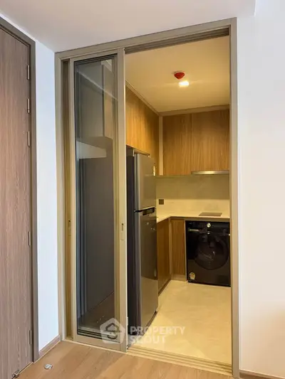 Modern kitchen with sleek appliances and wood cabinetry in a compact layout.