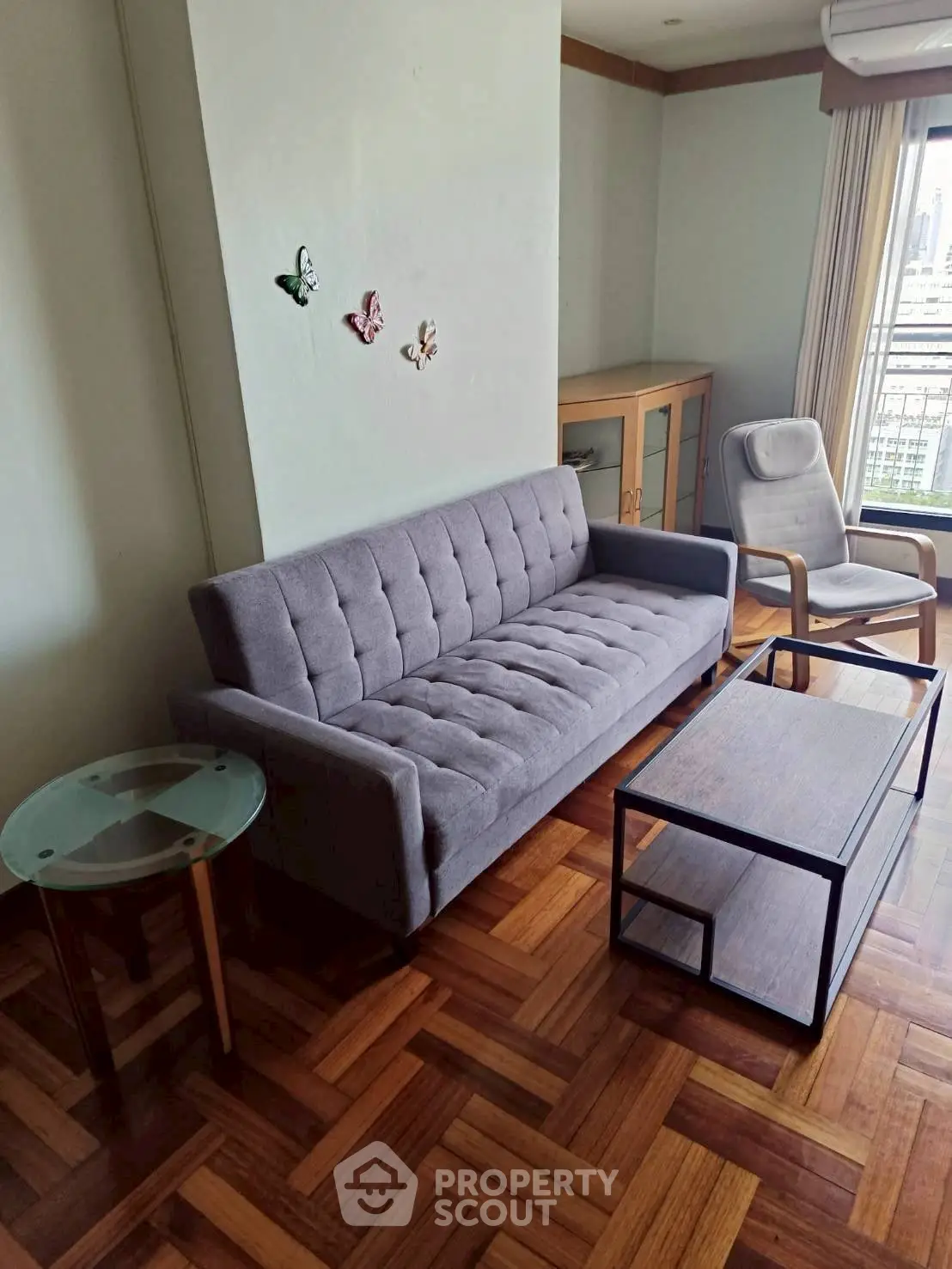 Stylish living room with parquet flooring, modern sofa, and city view window.