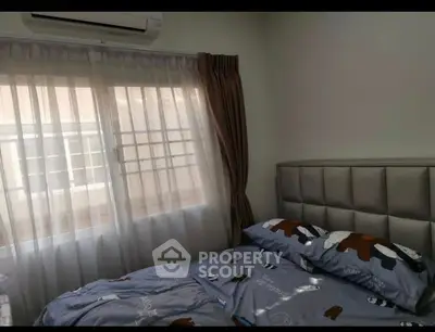 Cozy bedroom with plush headboard and large window with sheer curtains