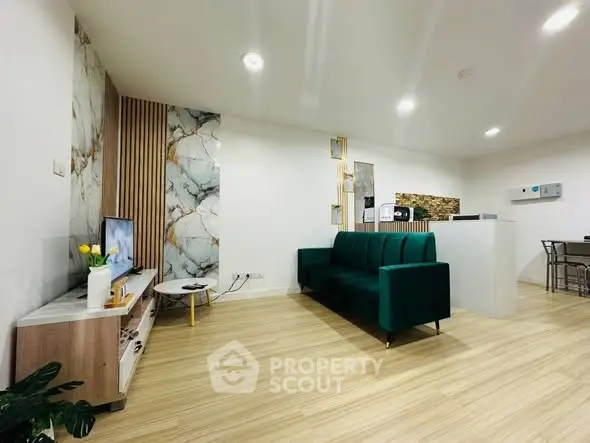 Modern living room with stylish decor and green sofa, featuring marble accent wall and wooden flooring.