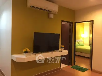Modern living room with wall-mounted TV and view into cozy bedroom