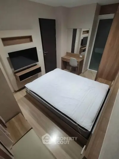 Modern bedroom with sleek furniture and built-in TV, perfect for urban living.