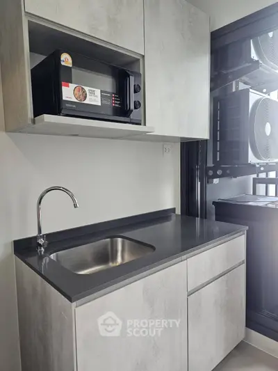 Modern compact kitchen with sleek cabinetry and built-in microwave