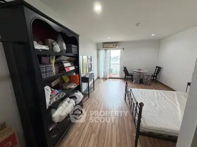 Spacious bedroom with wooden flooring and balcony access in modern apartment