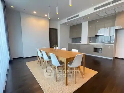 Spacious modern dining area with sleek kitchen in open layout, featuring elegant wooden table and chairs.