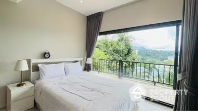 Spacious bedroom with stunning balcony view of lush greenery and mountains.