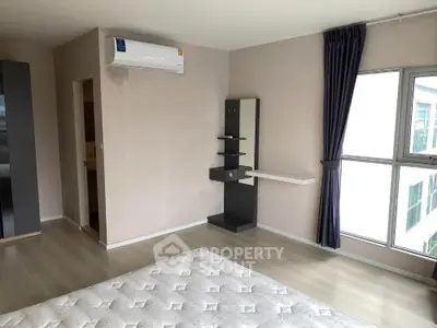 Spacious bedroom with modern air conditioning and large windows for natural light.