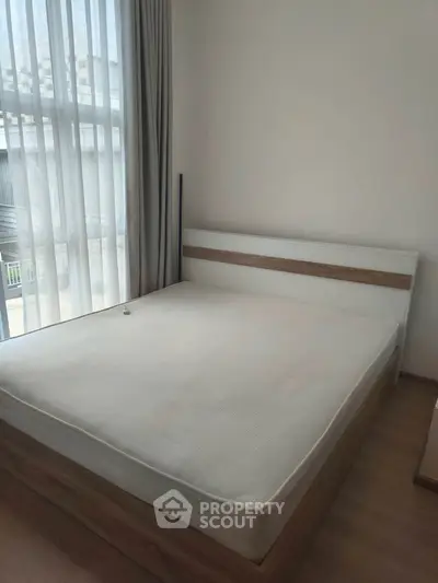 Spacious bedroom with large window and modern bed frame, perfect for natural light lovers.