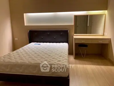 Modern bedroom with stylish bed and vanity, featuring warm lighting and sleek design.