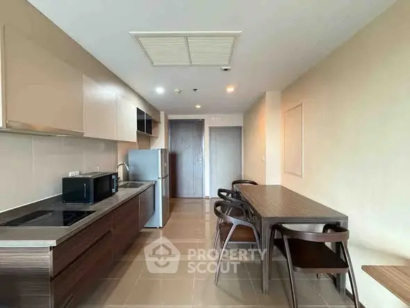 Modern kitchen with sleek cabinetry and dining area in open layout apartment.