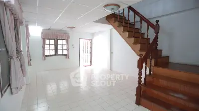 Spacious living room with wooden staircase and tiled floor in a bright home