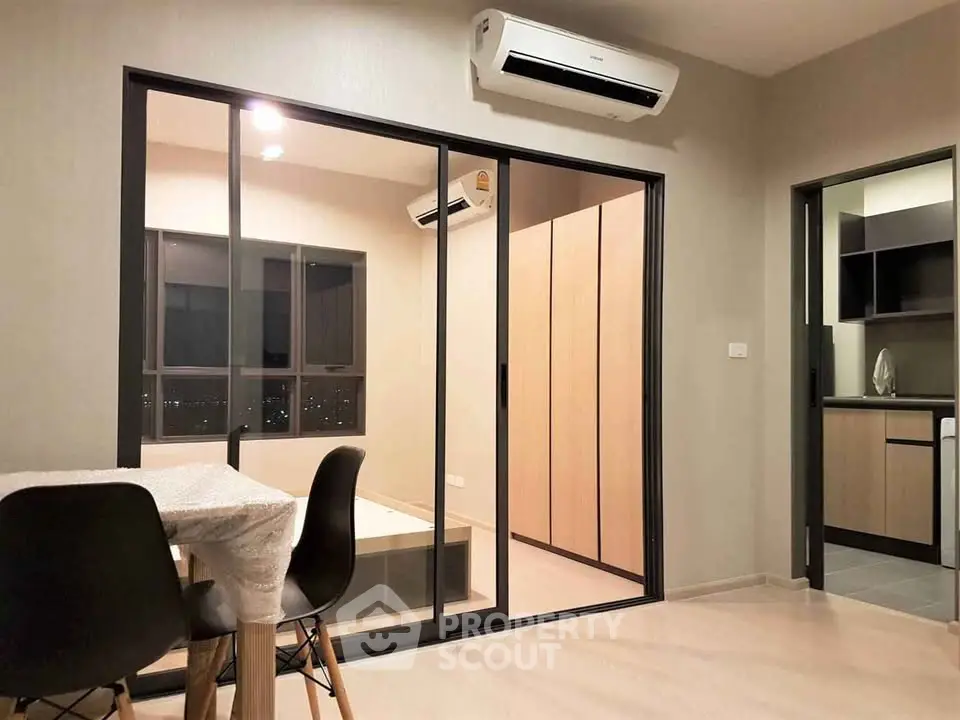 Modern apartment interior with dining area and sliding glass doors leading to bedroom.