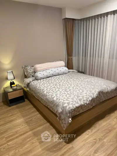 Cozy bedroom with modern decor and wooden flooring, featuring a comfortable bed and stylish bedside lamp.