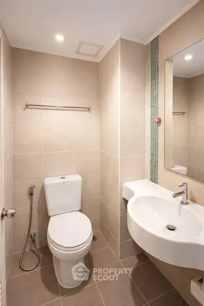 Modern bathroom with sleek fixtures and neutral tiles, featuring a wall-mounted sink and toilet.