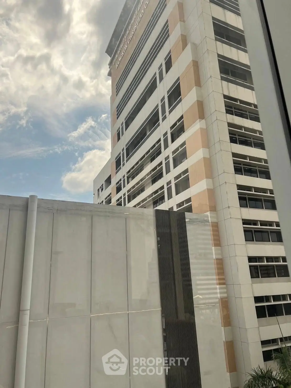 Modern high-rise building with sleek architecture under a partly cloudy sky.