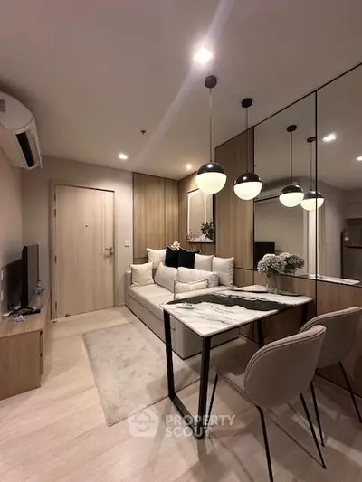 Modern living room with stylish decor and dining area, featuring elegant lighting and mirrored wall.