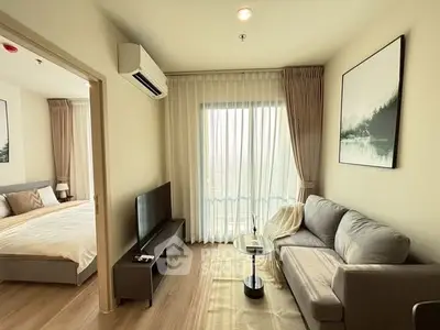Modern living room with cozy sofa, TV, and natural light next to a stylish bedroom.