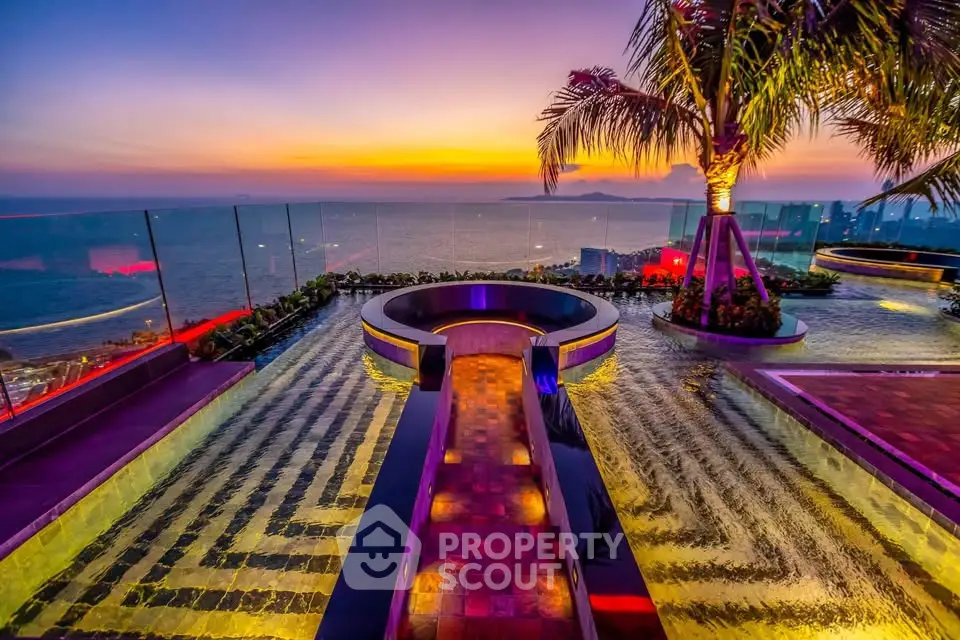 Stunning rooftop pool with panoramic ocean view at sunset, featuring modern design and lush palm trees.