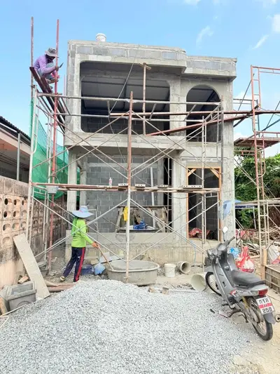 Modern two-story house under construction with scaffolding and workers on site.