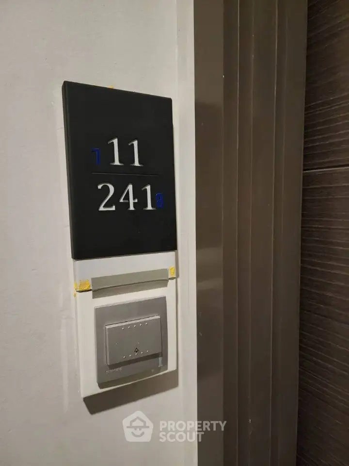 Modern apartment door number with sleek design and electronic doorbell.