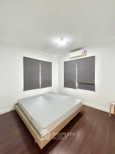 Minimalist bedroom with wooden flooring and air conditioning