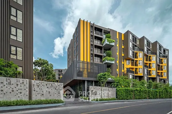 Modern apartment building with vibrant yellow accents and lush greenery.