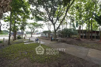 Spacious outdoor area with lush greenery and paved pathway, ideal for serene living.