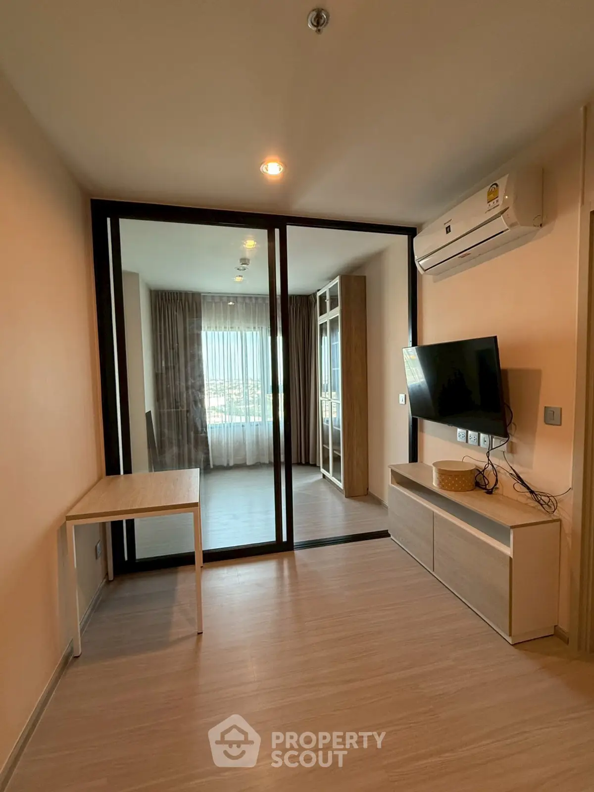 Modern living room with glass partition and wall-mounted TV in a stylish apartment.