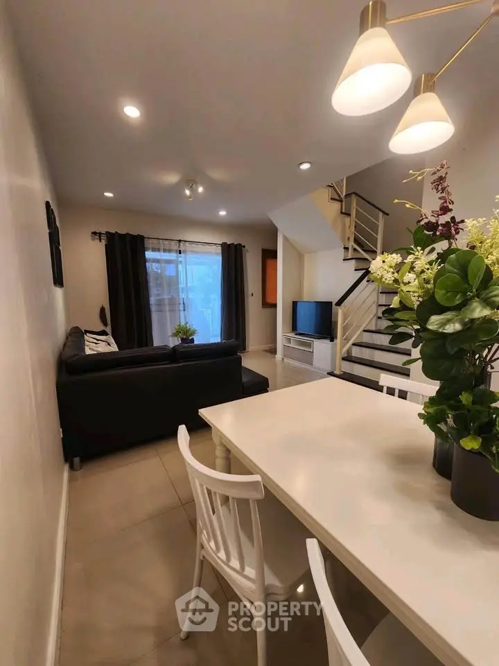Modern living room with stylish decor and staircase, featuring cozy seating and elegant lighting.