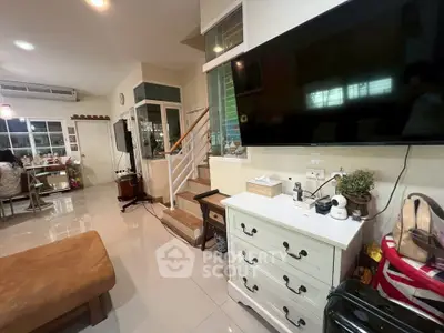 Spacious living room with modern decor and large TV, perfect for family gatherings.