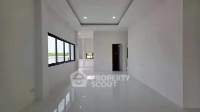 Spacious modern living room with large windows and sleek white tiles, offering abundant natural light.