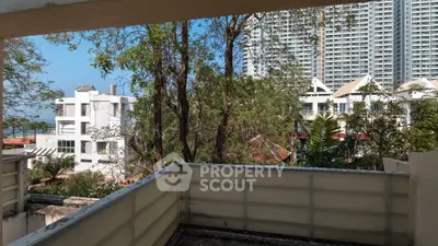 Spacious balcony with cityscape view and lush greenery, perfect for urban living.