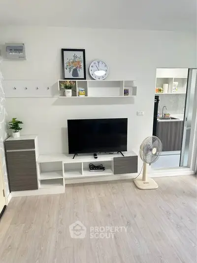 Modern living room with sleek TV stand, wall shelves, and stylish decor in a bright apartment.