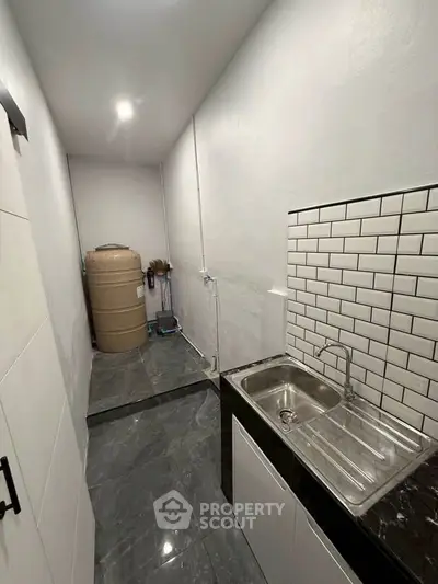 Compact kitchen with sleek sink and tiled backsplash in modern apartment