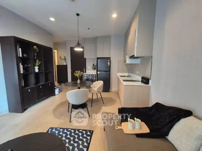 Modern living room with open kitchen, stylish furniture, and cozy decor in a contemporary apartment.