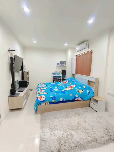 Cozy bedroom with modern decor, featuring a plush rug and entertainment setup.