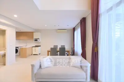 Spacious modern living room with open kitchen and dining area, featuring large windows and elegant curtains.