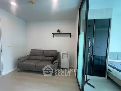 Modern living room with gray sofa and sliding glass door leading to bedroom