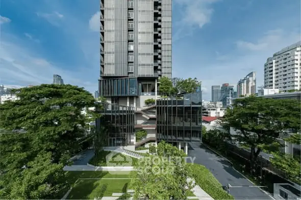 Modern high-rise building with lush green surroundings and cityscape view.