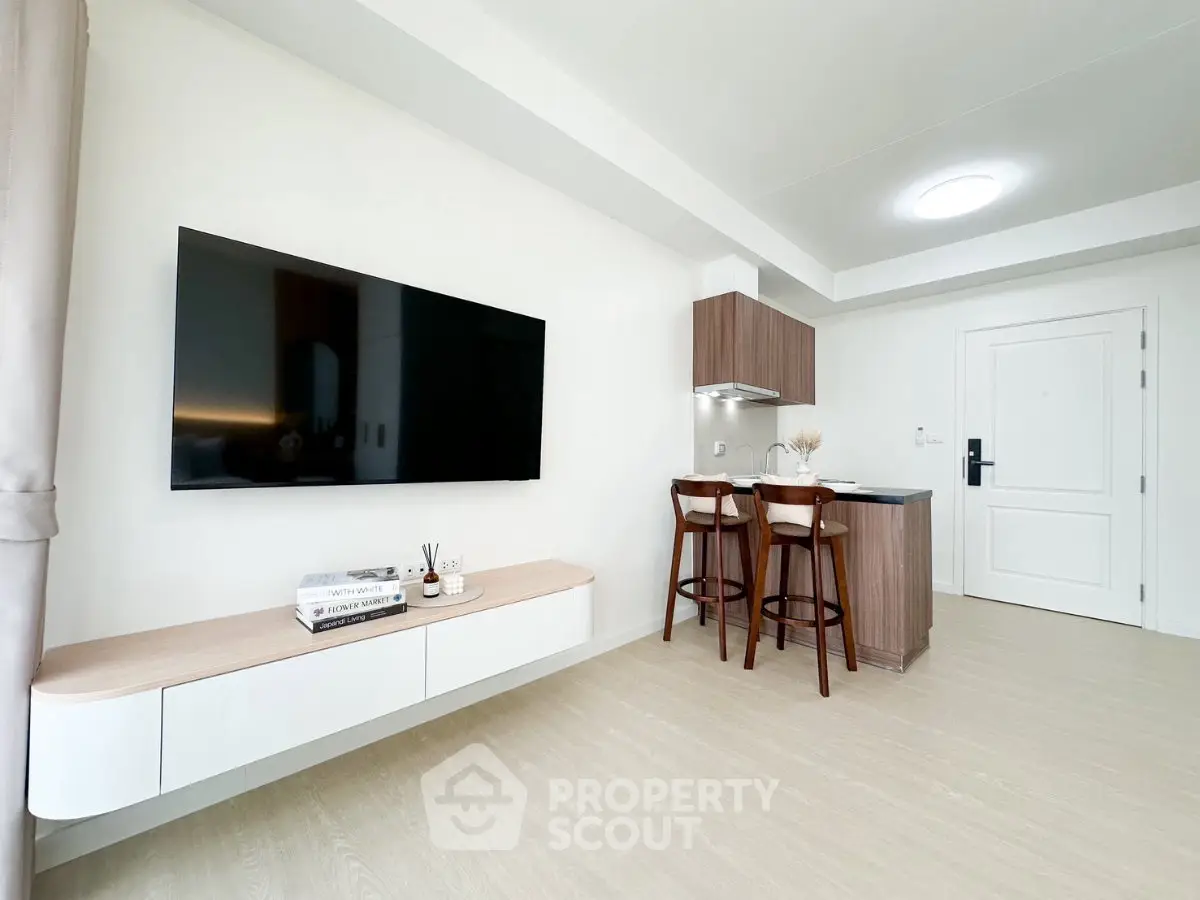 Modern minimalist living room with wall-mounted TV and compact kitchen area
