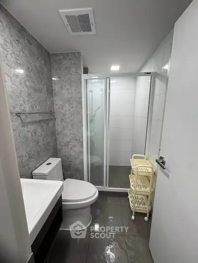 Modern bathroom with sleek shower and marble walls in contemporary apartment.