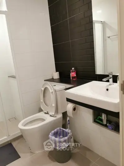 Modern bathroom with sleek black and white tiles, featuring a shower and contemporary fixtures.