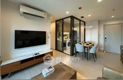 Modern living room with open kitchen and dining area, featuring sleek furniture and contemporary design.